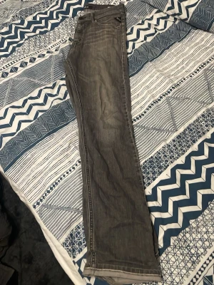 Grå bootcut jeans med slitningar - Snygga grå jeans med bootcut-passform och diskreta slitningar längs benen. Klassisk femficksmodell med dragkedja och knapp. Jeansen har en cool, tvättad look och är tillverkade i denim. Perfekta för en avslappnad och trendig stil.