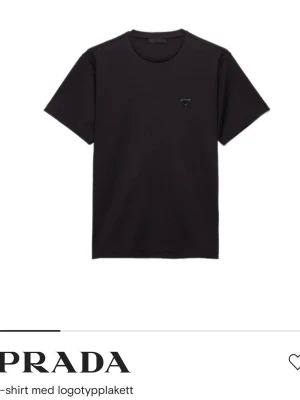 Svart t-shirt från Prada - Stilren svart t-shirt från Prada med liten logotypdetalj på bröstet. Klassisk rund halsringning och korta ärmar. Perfekt för en clean och modern look. 