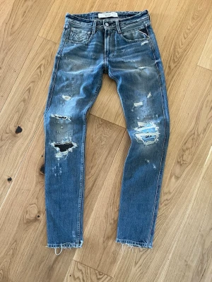 Replay Maestro jeans - Säljer ett par blå jeans från Replay med snygga slitningar och hål på benen. Jeansen är från Replays Maestro kollektion och är gjorda i hög kvalitet. Jeansen har fem fickor, raka ben och råa kanter vid bensluten. Perfekta för en avslappnad och trendig look. Storlek W28 L32. Tveka inte på att höra av er vid frågor eller funderingar 