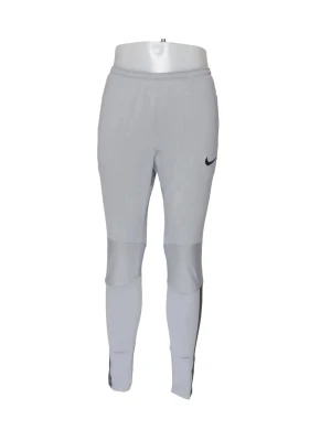 Grå träningsbyxor från Nike - Slimmade grå träningsbyxor från Nike med svart logga på låret. Byxorna har elastisk midja och paneler över knäna för extra rörlighet. Perfekta för träning eller sportaktiviteter. Tillverkade i ett lätt och stretchigt material.