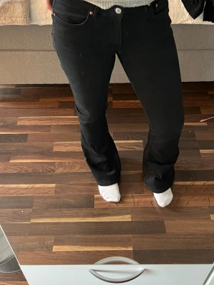 Svarta bootcut jeans  - Svarta jeans från Gina i modell bootcut med klassisk femficksdesign och dragkedjegylf. 