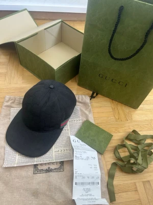 Svart keps från Gucci med GG-mönster - En svart Gucci keps köpt från Plick tror den är äkta har några skador så fråga för bilder men inget som syns. OBS! tillbehöret medföljer inte, kom med prisförslag vill helst få bort den 