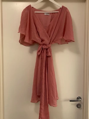 Godiva klänning - Jättefin och härlig rosa sommarklänning från Godiva London. Fjärilsärmar och knyt i midjan. Mindre vit fläck (ca 3mm) på vänstra kjolsidan, syns knappt, se bilder i slutet. Annars i jättefint skick!😍👌