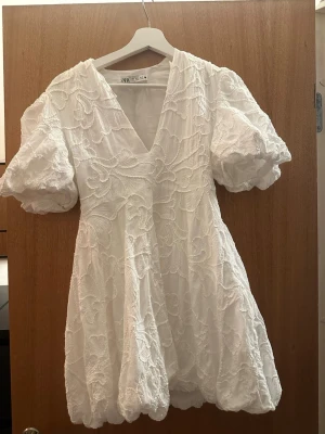 Zara studentklänning/ vit klänning - Säljer en vit broderad kort klänning från Zara med puffärmar och v-ringning i storlek S. Använd på min student förra året men är i perfekt skick. Perfekt för student eller sommarens alla tillfällen.🌸