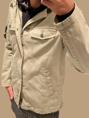 Beige parkajacka med fickor - Stilren feildjacka med två bröstfickor med knappar och två snedställda fickor framtill. Jackan har dragkedja och knappslå, samt lång ärm. Perfekt för dig som gillar en clean och avslappnad look. nu till sommaren den är ganska tunn så perfekt till sena sommar kvällar