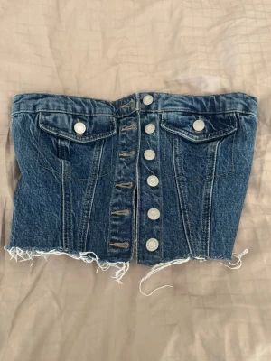 Blå denim tubtopp med knappar från Zara - Blå korsett topp i jeans från zara.