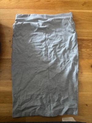 Grå långkjol med slits - En enkel och stilren grå långkjol i mjukt bomullsmaterial. Kjolen har en rak passform och en liten slits baktill. Lappen finns ej kvar men är strl L. 