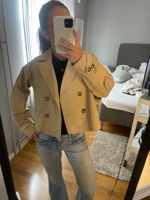 Kort beige trenchcoat med knappar - Snygg kort trenchcoat i beige från hm! Oanvänd 