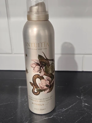 Rituals Intuita duschgelé 200 ml - Lyxig foaming shower gel från Rituals, Intuita-serien. Doft av sandelträ och vanilj. Flaskan är beige med vackert ormmotiv och blommor i rosa och grönt. Innehåller 200 ml. Perfekt för dig som vill ha en mjuk och väldoftande duschupplevelse.