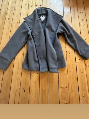 Grå ullrock med bred krage - En grå kort kappa med knappar och krage, perfekt till vår, sommar och höst! (Klädetiketen kommer jag klippa bort där det står mitt namn) bra material och väldigt fin! Säljer pågrund av att den är för liten för mig!☺️💗