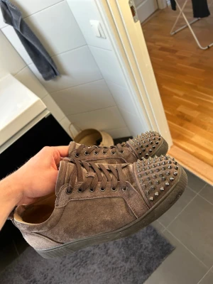 Brun gråa loubs - Christian Louboutin 44  i färgen bru och grå, sjukt snygga och den ända defekten är märken efter hälen på insidan men det är inget som syns eller känns. Kommer såklart att tvätta dem noggrant speciellt under skon vid köp om man är smidig!! Mvh Gardefasion