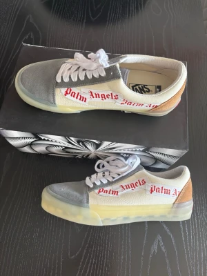 Palm Angels x Vans sneakers låga - Unika sneakers från Palm Angels x Vans med vit canvas, grå mocka framtill och beige/brun mockadetalj på hälen. De har använts max 3 gånger och är i väldigt bra skick!