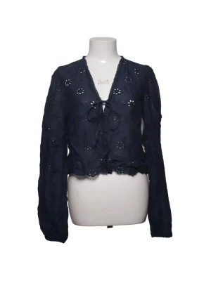 Mörkblå blus med broderade blommor från Nelly - Snygg mörkblå blus med broderade blommor och knytning framtill. Blusen har v-ringning, volangkant nertill och långa ärmar. Perfekt för en trendig och avslappnad look. Den är i storlek 38 och kommer från Nelly. Endast använd två gånger så i toppenskick.