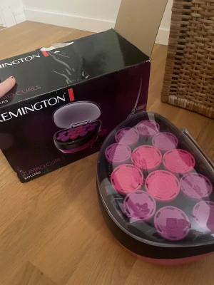 Remington Jumbo Curls värmespolar - Säljer ett set Remington Jumbo Curls värmespolar i svart och rosa/lila. Perfekt för att skapa stora, voluminösa lockar. Kommer i en smidig förvaringsbox med lock och elsladd. Innehåller flera spolar i två olika färger.