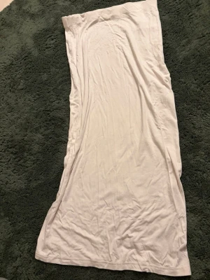 Beige långkjol från 157 - Beige långkjol från 157 i mjukt och stretchigt bomullstyg. Kjolen har en rak och enkel design med resår i midjan för en bekväm passform. Perfekt för en avslappnad och stilren look.