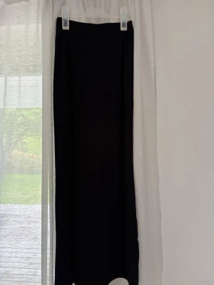 Svart långkjol  - En stilren svart långkjol med rak passform och låg midja. Kjolen är enfärgad och har en minimalistisk look som passar till många olika stilar. 