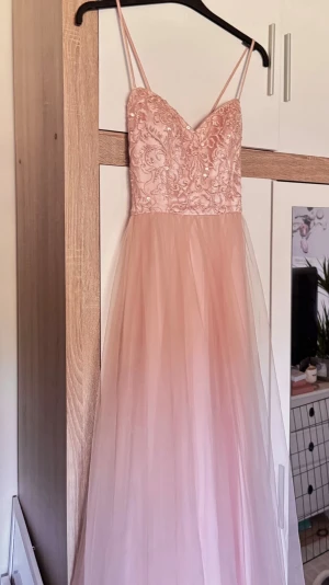 Ljusrosa långklänning med spetsliv - Säljer denna fina ljusrosa långklänning som jag köpte här på Plick för 700kr💗S/M från märket ” Morilee”. Säljer pågrund av att den tyvärr var för lång för mig (160cm).  Den har axelband som korsars i ryggen, men man kan även ta av dom ifall man vill det😊Passar perfekt för bal eller student. Pris kan diskuteras vid snabb affär🙏