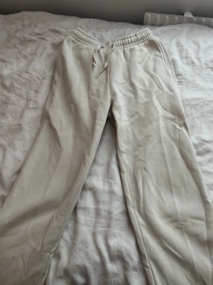 Beige mjukisbyxor från Gina Tricot - Säljer ett par beige mjukisbyxor från Gina Tricot, modell 'basically basic'. Byxorna har resår i midjan med dragsko och raka ben. Tillverkade i mjukt material som passar perfekt för chill dagar. Superenkla att matcha med hoodies eller t-shirts.