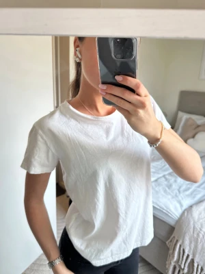 Vit  t-shirt från 157 - Vit t-shirt från 157 i 100% bomull. T-shirten har korta ärmar och rund halsringning, perfekt till jeans eller kjol för en clean och avslappnad look.