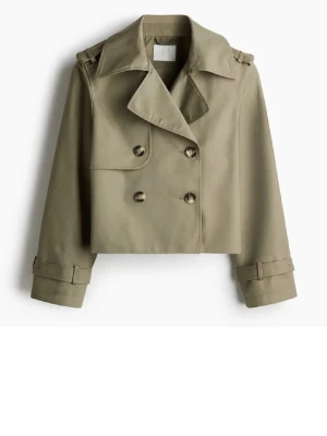 H&M Kort beige trenchcoat med dubbelknäppning - Stilren kort trenchcoat i grönt  med bred krage, axelklaffar och dubbelknäppning framtill. Jackan har långa ärmar med dekorativa spännen vid ärmsluten och en minimalistisk design. Använd 2 ggr är som ny. Är slutsåld 
