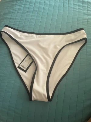 Vit bikiniunderdel med svarta kanter - Oanvänd vit bikiniunderdel från Lager 157 med kontrasterande svarta kanter.  