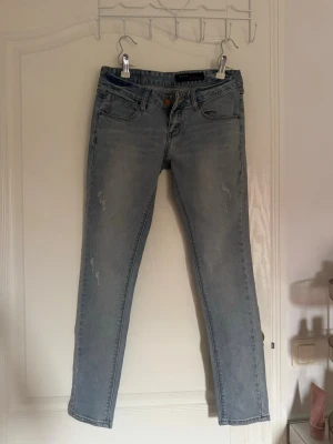 Ljusblå jeans  - Säljer ett par ljusblå jeans från utomlands med klassisk femficksdesign och smal passform. Jeansen har en snygg tvättad look och är tillverkade i mjukt denimtyg