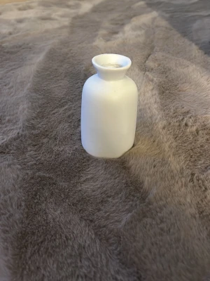 Vit liten keramikvas - Vit vas i keramik med rundad kropp och smal hals. Perfekt som dekoration eller för en liten blomma. Enkel och stilren design som passar i de flesta rum.