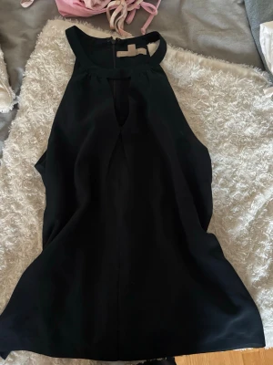 Svart ärmlös topp med nyckelhålsringning - Snygg svart ärmlös topp med nyckelhålsringning fram och hög hals.