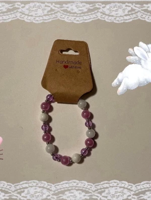 Två handgjorda pärlarmband - Säljer två söta handgjorda armband med pärlor. Ett armband har lila och vita pärlor, det andra har ljusrosa pärlor och en silverfärgad fjärilsberlock. Alla  armbanden är elastiska och perfekta för att ge din stil en gullig touch.