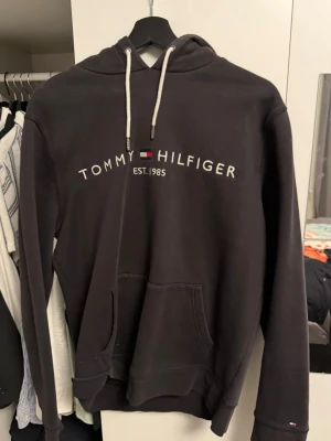 Svart hoodie från Tommy Hilfiger - Svart hoodie från märket Tommy Hilfiger. Tycker denna är extremt skön att ha, men tyvärr kommer den inte till så mycket använding längre. Hör gärna av er vid fler frågor!