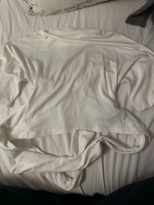 T-shirt med breda armar - Säljer denna vita t-shirt med breda armar och knytning i ryggen från gina tricot. Använd max 5 gånger och har en liten fläck på framsidan. 