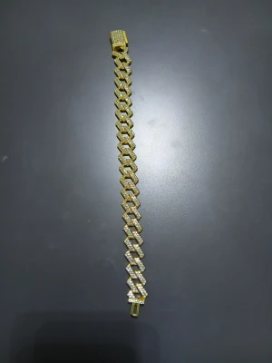 Guldigt kedjearmband med stenar - Snyggt armband i guldfärgad metall med breda, platta länkar täckta av glittrande stenar. Armbandet har ett rektangulärt lås som också är dekorerat med små stenar för extra bling. Perfekt för dig som gillar statement-smycken. Pris kan diskuteras!! armbandet är 23cm lång.