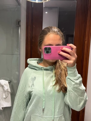 Mintgrön hoodie från Ami Paris - Snygg mintgrön hoodie från Ami Paris med klassisk huva och dragsnören. På bröstet finns det ikoniska Ami-hjärtat. Hoodien har ribbade muddar vid ärmar och nederkant samt en magficka. Perfekt för en chill och trendig look. Pris kan diskuteras❤️