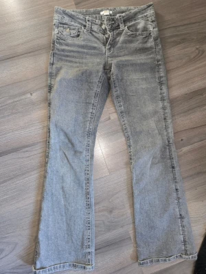 Grå bootcut jeans från Gina Tricot - Säljer ett par grå bootcut jeans från Gina Tricot. Jeansen har klassisk femficksdesign, knapp och dragkedja framtill samt snyggt tvättad look. Perfekta för dig som gillar en avslappnad och trendig stil. Lite slitna mellan benen se bild ,  går nog och fixa för den som kan. 
