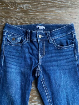 Mörkblå jeans med kontrastsömmar - Snygga mörkblå jeans med vita kontrastsömmar och klassisk femficksdesign. Jeansen har ficklock med knapp bak och en liten myntficka fram. Tillverkade i ett mjukt denimtyg som ger en bekväm passform. Perfekta för en avslappnad och trendig look. dieseln är en jättefin mörkblå färg och Stockholm still 