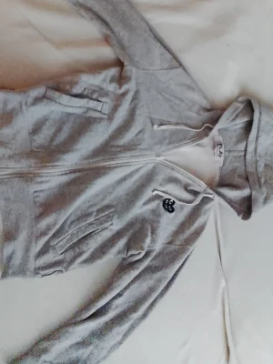 Grey hoodie, Comme des Garçons PLAY “Double Heart” - Säljer en Comme des Garçons PLAY “Double Heart”. På bröstet finns ett svart hjärta med ögonbrodyr. Hoodien har vita dragsnören och två fickor framtill. Nypris ligger på 3000-3500 