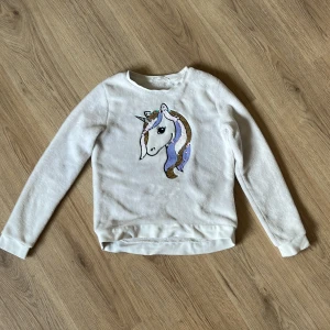 Enhörnings tröja - Jag säljer denna väldigt söta tröja, den är från hm men är köpt för väldigt länge sedan. Enhörningen har paljetter som går att dra på och då ändrar den färg. Materialet är väldigt skönt och fluffigt så perfekt för lite kallare dagar. Den har två fläckar som syns på bild 2,3 men annars är den i bra skick. Priset går att diskutera, skriv till mig om ni har frågor. 