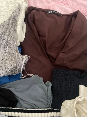 Mystery bag fylld med kläder! - 3 klänningar, 2 blusar, 2 koftor, 3 bodys och 4 toppar. Har lagt till 3 toppar i det men som ej är med i bilden. Sammanlagt 17 plagg. Plaggen säljs ej separat. Kan ej skicka bild på separata plagg då det är en mystery bag. Flertalet olika märken i den, bland annat NA-KD och Zara. Storlekarna varierar allt mellan XXS och M, mest S och XS men allt har passat mig som varierar mellan XS och S.