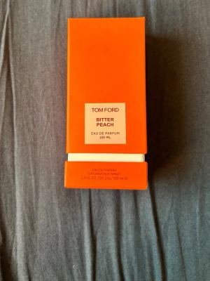 Tom Ford Bitter Peach EdP 100 ml - Tom Ford Bitter Peach Eau de Parfum i en snygg orange förpackning. Flaskan rymmer 100 ml och doften är känd för sina fruktiga och sensuella noter. Perfekt för dig som vill sticka ut med en unik och lyxig parfym. Använt typ 20% av den så ca 80 ml är kvar. Fick den som present men kommer tyvärr inte till användning mer. Nypris: 5 500 kr säljer för 3 000 kr. Vid snabb o smidig affär kan priset diskuteras 