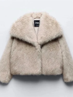 Beige fuskpälsjacka från Zara - Säljer en fluffig beige fuskpälsjacka från Zara med bred krage och rak passform. Jackan har långa ärmar och är supermjuk, perfekt för att hålla värmen under kalla dagar. Enkel att styla och ger en lyxig känsla till din outfit.