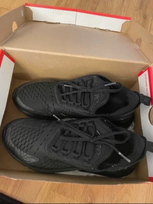 Nike Air Max 270 helsvarta sneakers - Säljer ett par helsvarta Nike Air Max 270 sneakers med mesh-överdel och synlig Air-enhet i hälen. Skorna har en sportig look med diskreta loggor och snörning de är väldigt bekväma. Är i storlek 38,5. Använts ett få tal gånger.