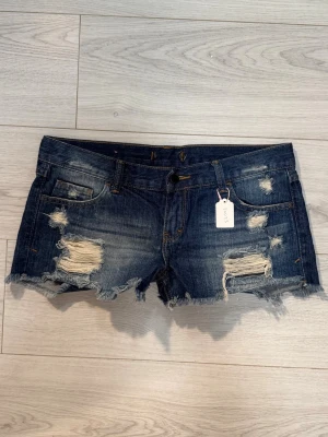Low jeansshorts med slitningar 20053 - Midjemått: 42cm. Gren: 19cm. (Storlek saknas, men uppskattas padda M/L. Kolla in min profil, följ för fler plagg🙌