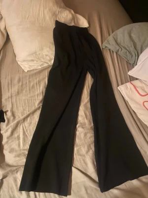 Svarta vida leggings med hög midja - Säljer ett par svarta leggings med hög midja och utsvängda ben. De är stretchiga och sitter bekvämt, perfekta för en trendig och avslappnad look. Passar till både sneakers och boots.
