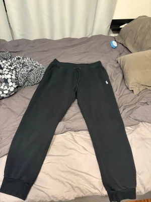 Svarta Ralph lauren double knit mjukisbyxor  - Svarta mjukisbyxor med resår i midjan och benslut samt dragsko. Liten vit logga på vänster lår. Byxorna har en avslappnad passform och är tillverkade i mjukt material, perfekta för chill dagar.