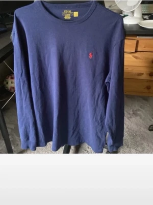 Blå långärmad tröja Polo Ralph Lauren helt ny - Snygg blå långärmad tröja från Polo Ralph Lauren i klassisk passform. Tröjan har rund halsringning och den ikoniska röda logotypen broderad på bröstet. Tillverkad i mjukt bomullsmaterial som känns skönt mot huden.