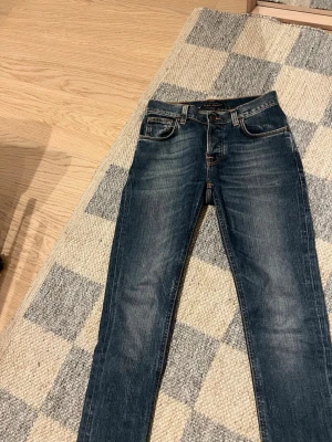 Mörkblå jeans från Nudie Jeans - W29 L32 , modell: grim thim                                Säljer ett par mörkblå jeans från Nudie Jeans med klassisk femficksmodell och snygga slitningar framtill. 