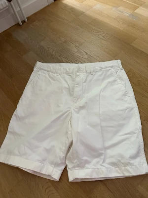 Vita klassiska bomullsshorts stl M i mycket fint skick  - Snygga vita shorts i bomull med normal passform och midja. De har bälteshällor, sidofickor och bakfickor med knapp. Perfekta för varma dagar och enkel att matcha med olika stilar.