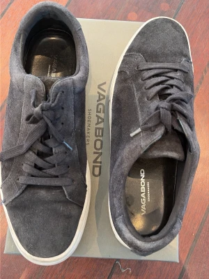 Blåa Vagabond sneakers i mocka - Snygga svarta sneakers från Vagabond i mocka med klassisk låg profil och vita sulor. Skorna har svarta skosnören och diskret branding på innersulan. Perfekta för en stilren och avslappnad look.