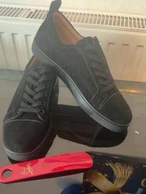 Svarta mockasneakers med låg profil - Stilrena christian louboutin  mocka med lågt skaft och svarta skosnören. Klassisk design med rund tå och diskreta sömmar. Insidan är ljusbrun och sulan är svart. Perfekta för dig som gillar en clean och tidlös look.