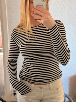 Svartvit randig ribbad långärmad topp - Säljer en svartvit långärmad topp med smala horisontella ränder. Toppen är ribbad och har en kroppsnära passform med rund halsringning.